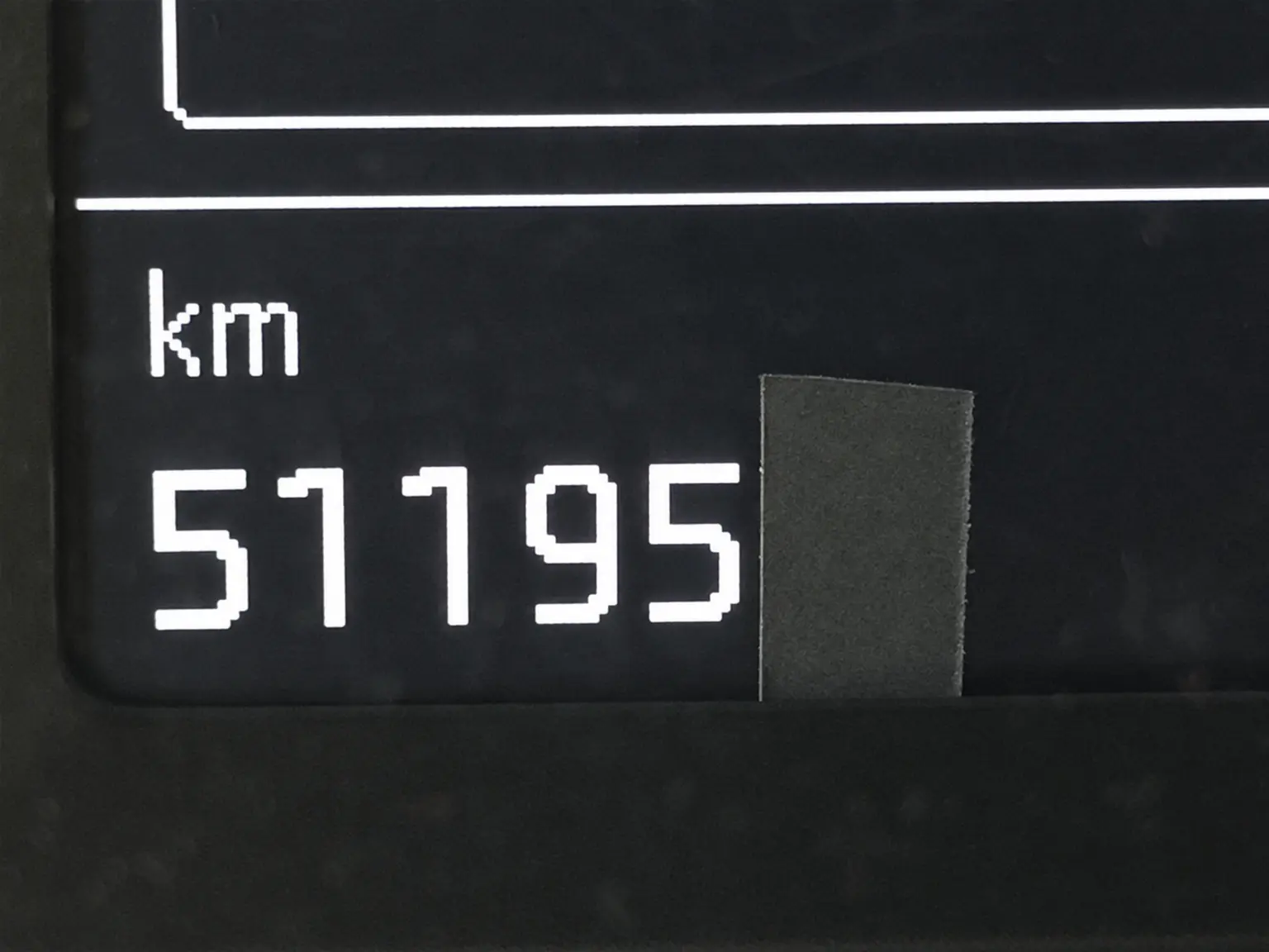 Fotografie vyhotovené poistným technikom zobrazujúce stav odometra, na ktorých je viditeľná lepiaca páska schválne zakrývajúca skutočný nájazd kilometrov.